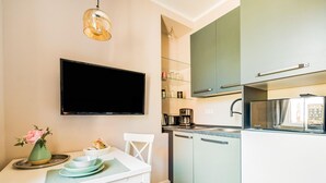 Een moderne keuken met een flatscreen-tv, een koffiezetapparaat en een magnetron.