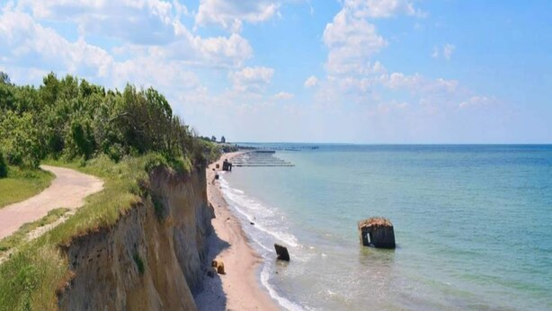 A coastal road with a cliffside on one side and a beach on the other, leading to the sea. - Chalet in Wendorf (Kuhlen-Wendorf)