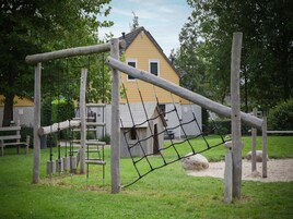 Un parque infantil con estructuras de madera y un edificio amarillo al fondo.