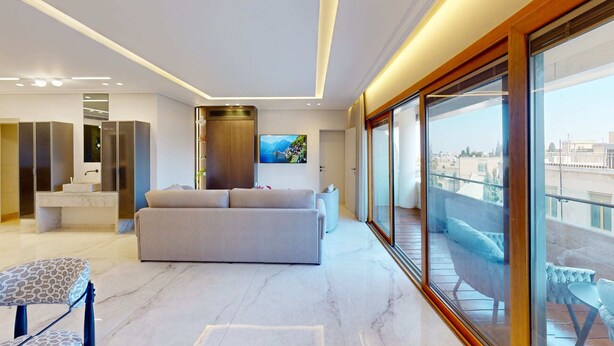 Una sala de estar moderna con un sofá, un televisor y un balcón con vistas a la ciudad.