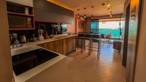 A modern kitchen with a view of the ocean, featuring a bar area and a dining space.
