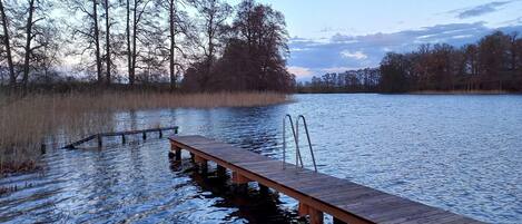 A wooden dock extending into a calm lake surrounded by trees.
