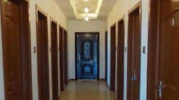 Un pasillo largo y estrecho con puertas de madera a ambos lados, que conduce a una habitación oscura al final.