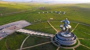 Vue aérienne d’un parc avec un monument central, des allées et des champs verdoyants tout autour.