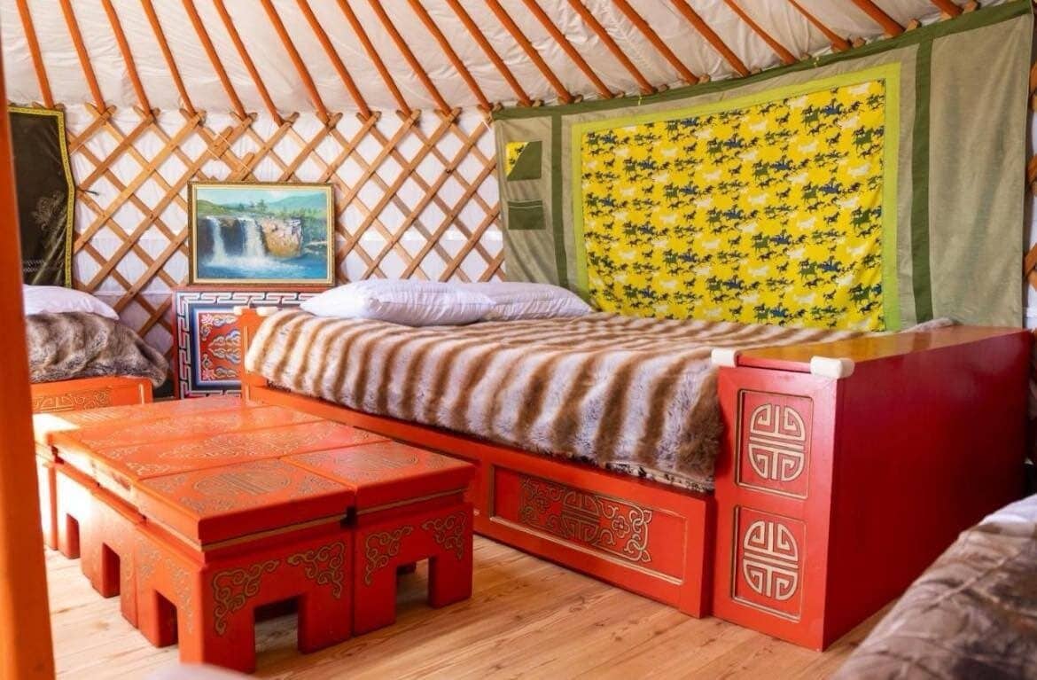 Een knus ingerichte kamer met een bed, een klein tafeltje en een bankje.