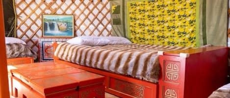 Een knus ingerichte kamer met een bed, een klein tafeltje en een bankje.