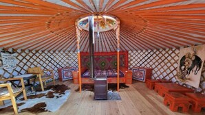 L’intérieur d’une yourte traditionnelle, avec un lit au centre, des meubles en bois et un mur décoratif.