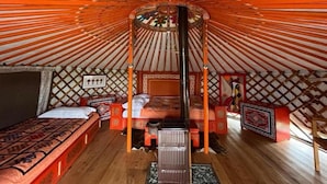 L’intérieur d’une yourte traditionnelle, avec un lit au centre, un plancher en bois et un plafond décoratif.