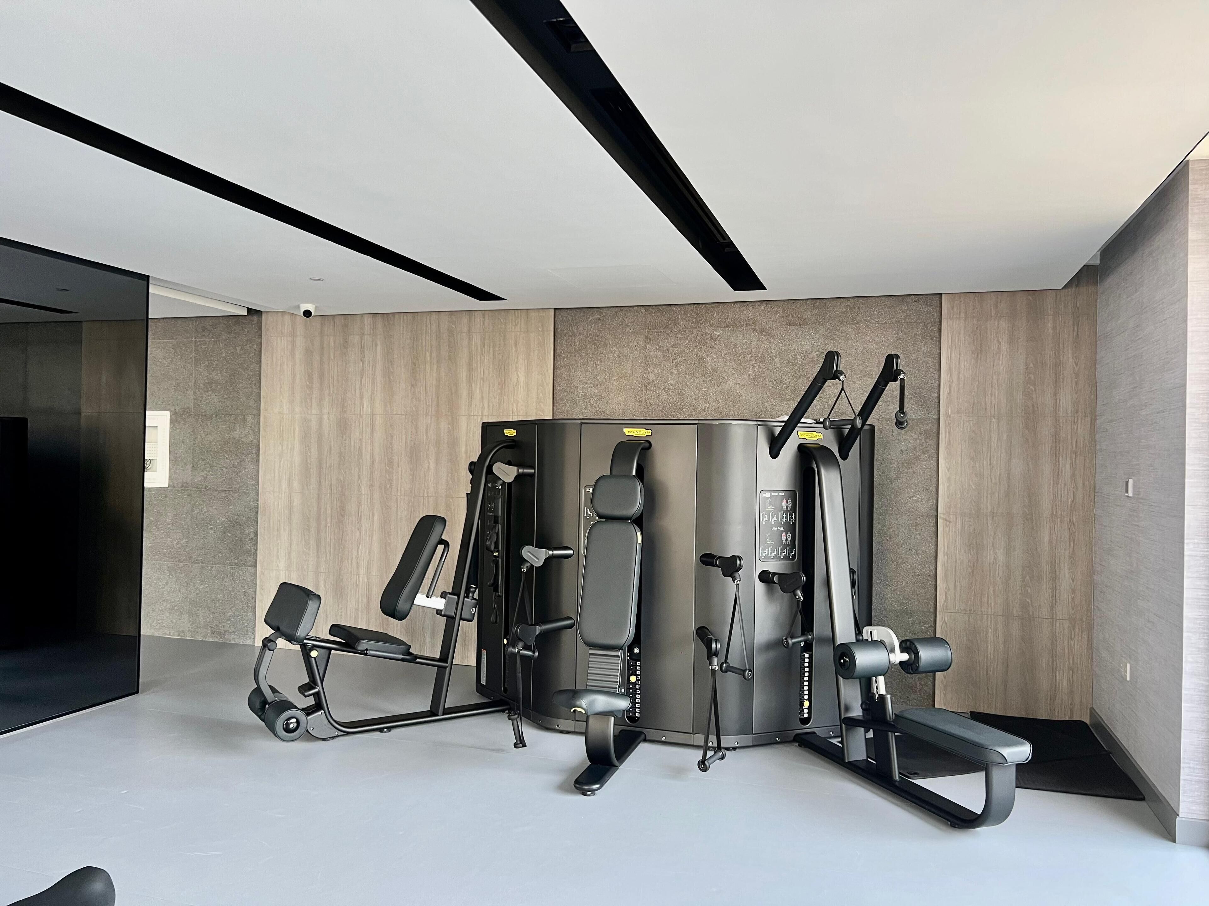 Une salle de sport moderne dotée d’une variété d’équipements d’entraînement, notamment un support à squats, un banc de développé couché et des appareils à câbles.