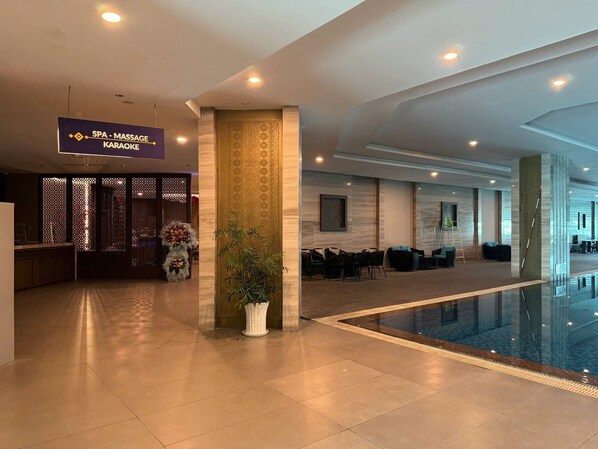 A hotel lobby with a reception desk, a spa-massage area, and a pool. - Apartment PHONGLIEM 2 (Nha Trang)