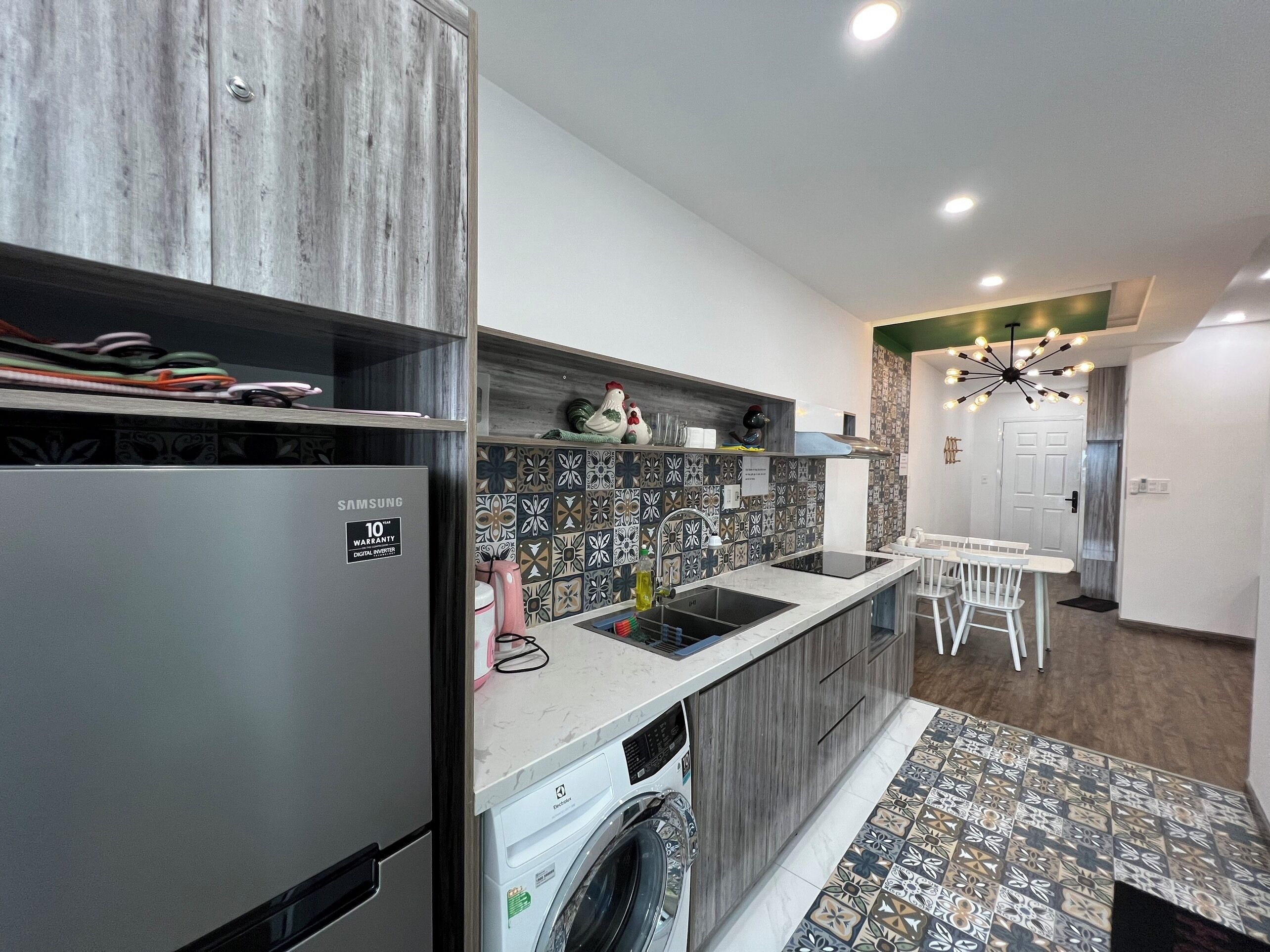 A modern kitchen with a built-in washing machine, a stainless steel refrigerator, and a patterned backsplash.