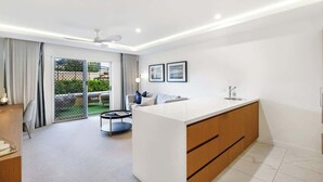 Une cuisine moderne dotée d’un îlot central, d’un coin repas avec une table ronde et d’une porte-fenêtre coulissante donnant sur une terrasse.