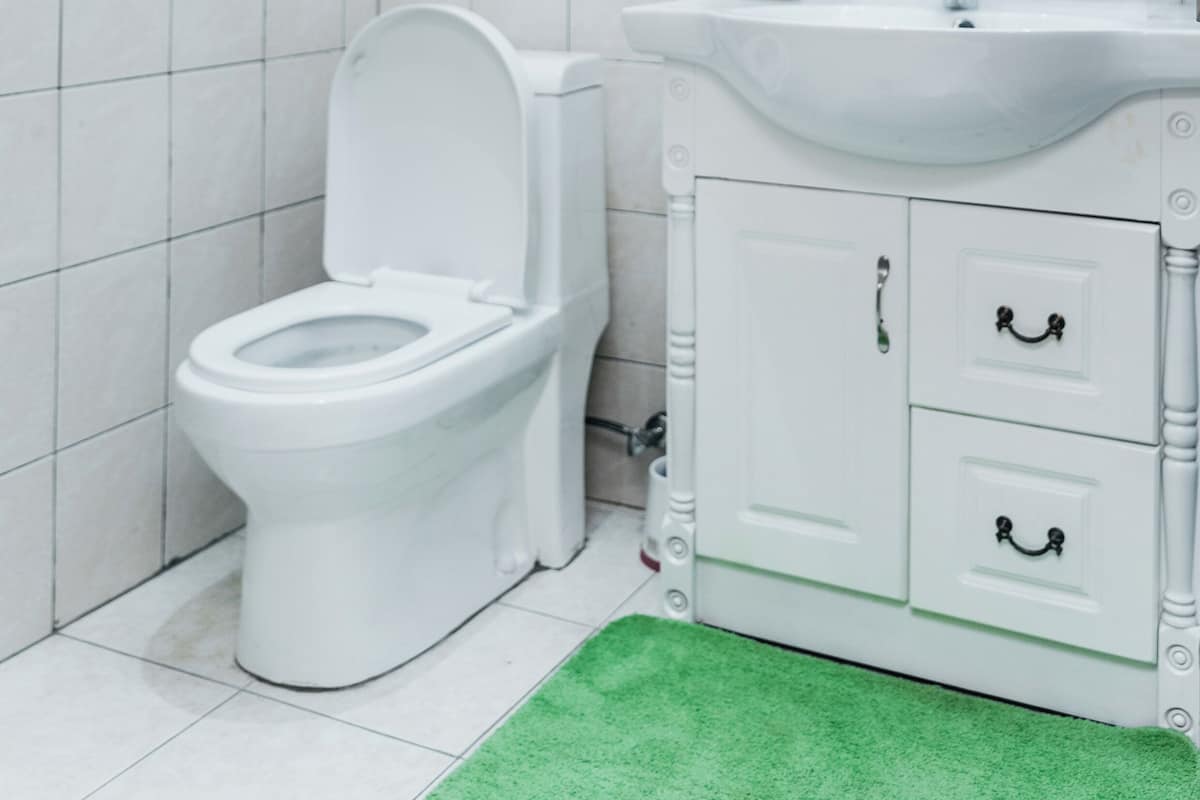 Een badkamer met een wit toilet, een witte wastafel en een kast met lades.