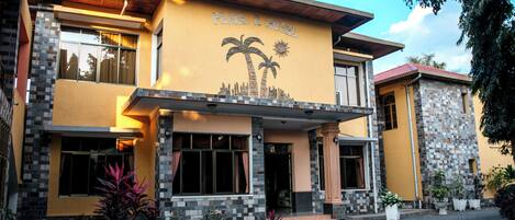 A hotel with a prominent sign reading "PEARL HOTEL" and a palm tree motif on the facade.