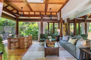 A spacious indoor area with a wooden ceiling, a sofa, a coffee table, and a Buddha statue.
