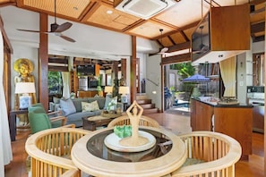 A spacious living area with a central round table, a sofa set, and a staircase leading to an upper level.