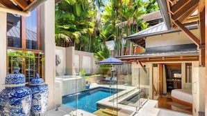 Un área de piscina moderna con barreras de cristal, una piscina pequeña y grandes jarrones decorativos.