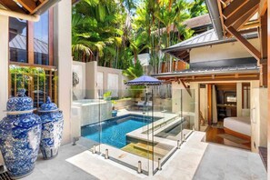 A modern pool area with glass barriers, a small pool, and large decorative vases.