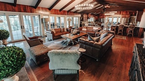 A spacious living room with a large sofa, a coffee table, and a fireplace. There is a kitchen area with modern appliances and a dining area with bar stools. - Spacious lakeview lodge on Lake Cumberland with WiFi, AC (Seventy Six)