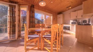 Un intérieur en bois comprenant une table et des chaises, un coin cuisine et de grandes fenêtres.