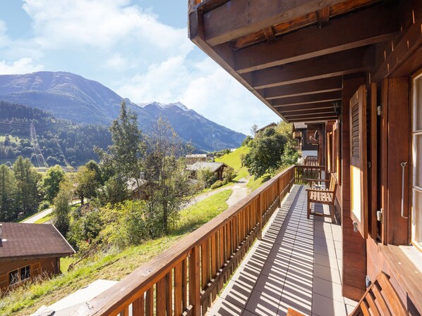 Un balcón de madera con vista a un paisaje montañoso.