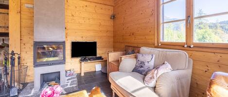 A cozy cabin interior with a wooden interior, a fireplace, a sofa, and a television.