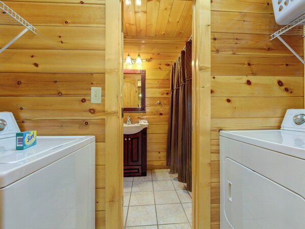 Un baño de cabaña de madera con un lavabo, un espejo y dos lavadoras.