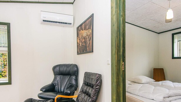 A room with a bed, a chair, a small table, an air conditioning unit, and a framed picture on the wall. - 4 Star Holiday Home in Hovborg (Hovborg)