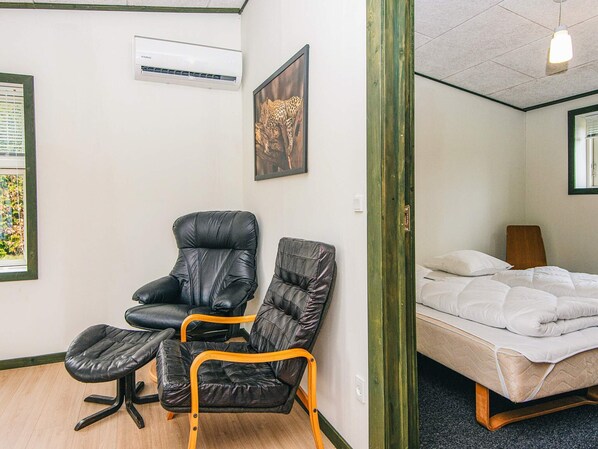 A room with a bed, a chair, a small table, an air conditioning unit, and a framed picture on the wall. - 4 Star Holiday Home in Hovborg (Hovborg)