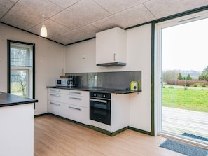 A modern kitchen with a black countertop, white cabinets, and a built-in oven. - 4 Star Holiday Home in Hovborg (Hovborg)