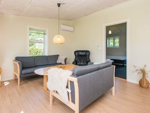 A modern living room with a grey sofa, a wooden coffee table, and a black leather chair. - 4 Star Holiday Home in Hovborg (Hovborg)