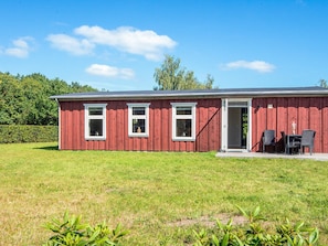 A red building with three windows and a door, a small patio with chairs, and a grassy yard. - 4 Star Holiday Home in Hovborg (Hovborg)