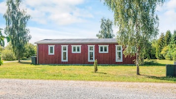 A red building with a gravel driveway and a small tree in front.