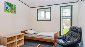 A dormitory room with a single bed, a wooden desk, a black chair, and two windows with blinds. - 4 Star Holiday Home in Hovborg (Hovborg)