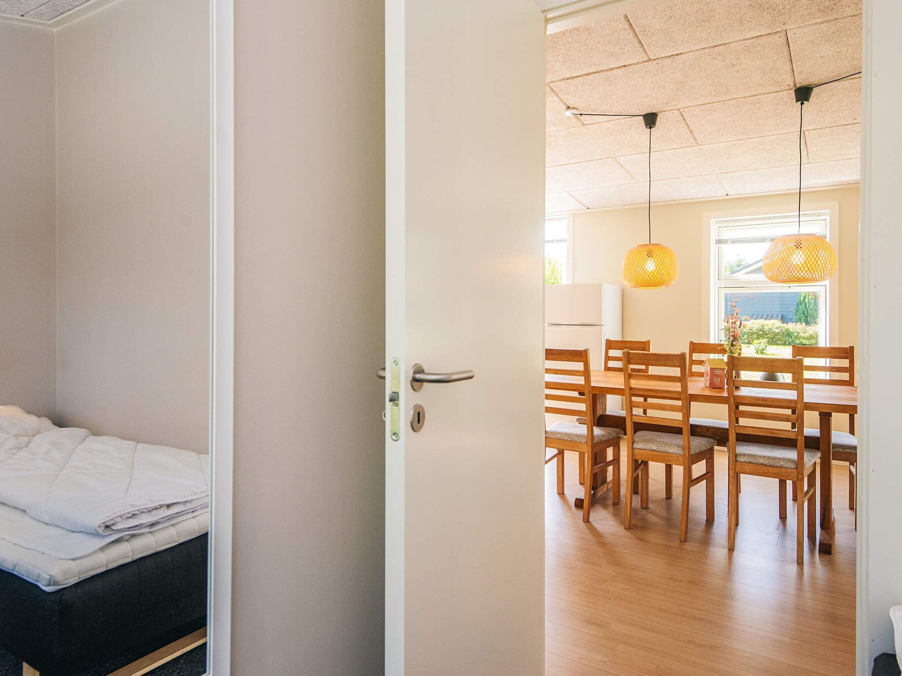 Una habitación con una cama, un comedor con sillas y una mesa de madera, y vistas al exterior a través de una ventana.
