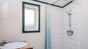 A small bathroom with a window, a shower, and a sink. - 4 Star Holiday Home in Hovborg (Hovborg)