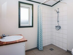 A small bathroom with a window, a shower, and a sink. - 4 Star Holiday Home in Hovborg (Hovborg)