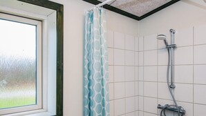 A bathroom with a shower, a window, and a patterned curtain. - 4 Star Holiday Home in Hovborg (Hovborg)