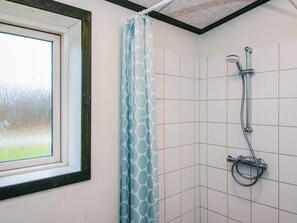 A bathroom with a shower, a window, and a patterned curtain. - 4 Star Holiday Home in Hovborg (Hovborg)