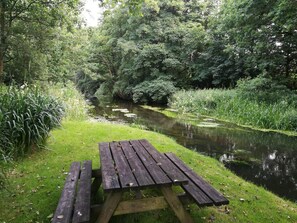A picnic table by a calm river surrounded by lush greenery. - 4 Star Holiday Home in Hovborg (Hovborg)