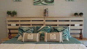 A neatly arranged bedroom with a bed, a wooden headboard, and three wall-mounted abstract paintings. - Riumar Nature 38, villa at 100 meters from the beach in the urbanization of Riumar.  (Riumar)