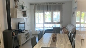 A modern kitchen with a central island, a dining area with a long table and chairs, and a living area with a sofa and a TV. - Riumar Nature 38, villa at 100 meters from the beach in the urbanization of Riumar.  (Riumar)