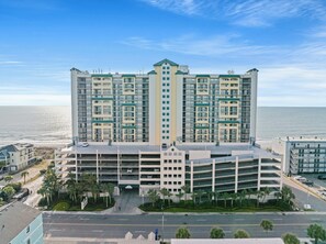 A high-rise hotel with multiple floors, a parking garage, and a view of the ocean. - Ocean Bay Club 102 4BR OF Condo Close to Main St (North Myrtle Beach)