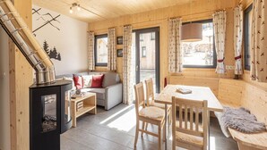 A cozy cabin interior with a wooden interior, a fireplace, a sofa, a dining table, and chairs. - Inviting Chalet With Terrace (Sankt Georgen am Kreischberg)