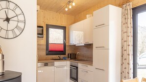 A modern kitchen with white cabinets, a black clock, and a window with red blinds. - Inviting Chalet With Terrace (Sankt Georgen am Kreischberg)