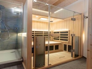 Relax in a compact sauna room with a glass-enclosed shower area and a bench for seating.