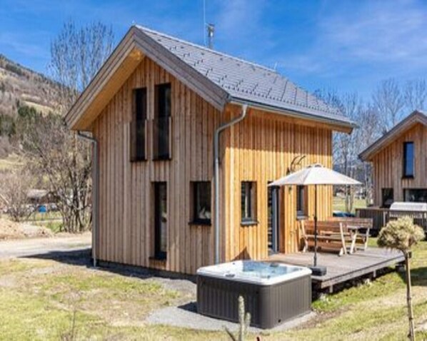 Eine Holzhütte mit Whirlpool und einer Terrasse.