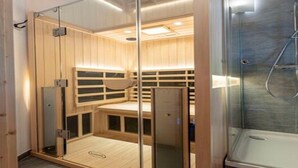 A sauna with glass walls, wooden benches, and a separate shower area. - Inviting Chalet With Terrace (Sankt Georgen am Kreischberg)