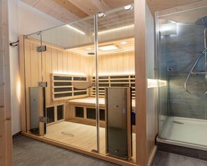 Relax in a serene sauna room with a glass enclosure and separate shower area.