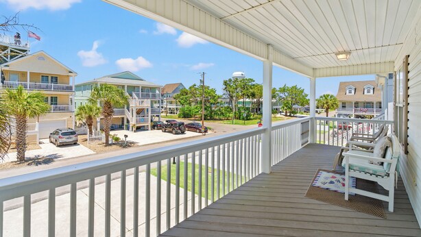 A covered porch with a view of a street, a white railing, and a bench. - Bubba's Beach Blessing - 4BR/2BA- Pet Friendly (North Myrtle Beach)